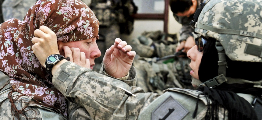 U.S. Army Maj. Rosemary Reed of the Khowst Provincial Reconstruction Team helps U.S. Army Sgt. 1st Class Paula Reill of the 3-19th Indiana Agricultural Development Team with her head scarf.