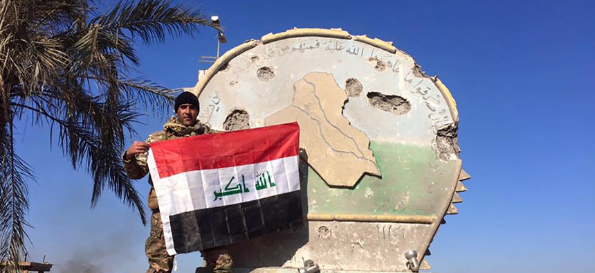 An Iraqi soldier holds a national flag in the government complex in central Ramadi, 70 miles (115 kilometers) west of Baghdad, Iraq, Monday, Dec. 28, 2015.