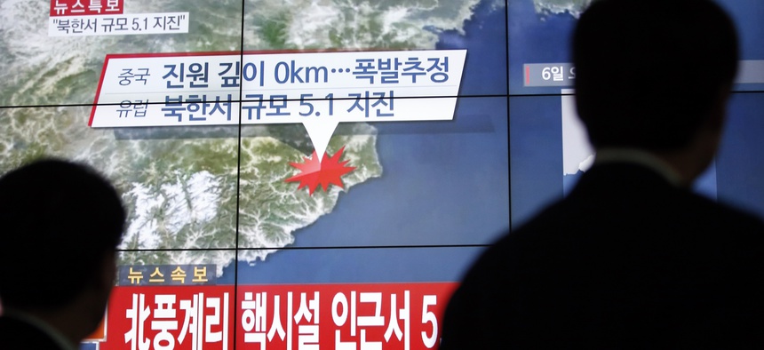 People walk by a screen showing the news reporting about an earthquake near North Korea's nuclear facility, in Seoul, South Korea, Wednesday, Jan. 6, 2016.