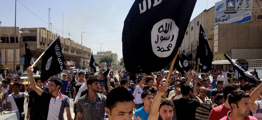 In this June 16, 2014 file photo, demonstrators chant pro-Islamic State group, slogans as they carry the group's flags in front of the provincial government headquarters in Mosul.