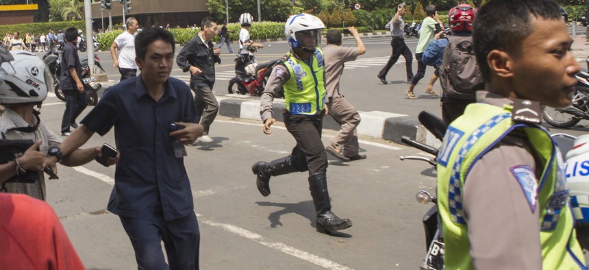 People, including unarmed police officers, flee from the scene after a gun battle broke out following an explosion in Jakarta, Indonesia Thursday, Jan. 14, 2016.