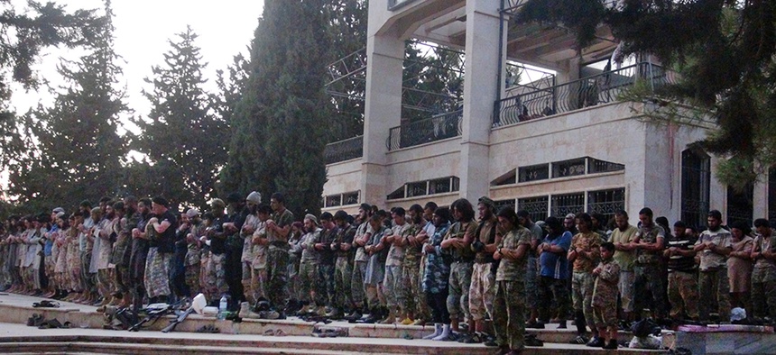 In this undated file photo posted on Wednesday, Aug. 27, 2014 by the Raqqa Media Center of the Islamic State group, fighters from ISIS pray at the Tabqa air base after capturing it from the Syrian government in Raqqa, Syria.