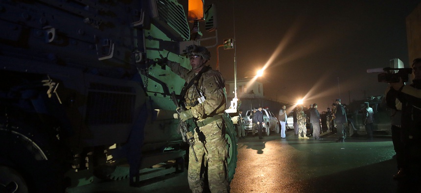 A U.S. soldier stands near his vehicle at the site of a suicide attack near a compound belonging to foreigners in Kabul, Afghanistan, Monday, Jan. 4, 2016.