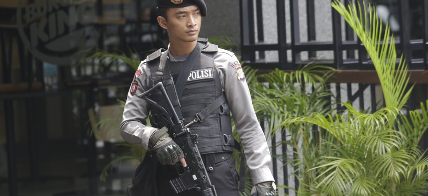 An armed policeman stands in front of a Burger King restaurant near the Starbucks cafe where Thursday's attack occurred in Jakarta, Indonesia, on Friday, Jan. 15, 2016.