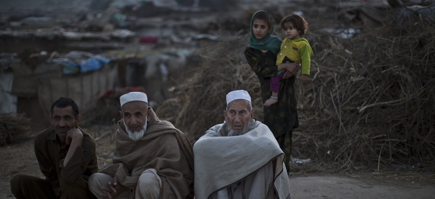 Pakistani men, who were displaced with their families from Pakistan's tribal areas due to fighting between the Taliban and the army, sit on a roadside on the outskirts of Islamabad, Pakistan, Saturday, Nov. 2, 2013.