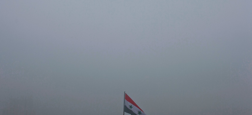 A Syrian national flag waves as heavy fog envelops the capital city of Damascus, Syria, Wednesday, Feb. 24, 2016.
