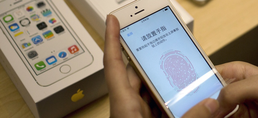 In this Sept. 20, 2013 file photo, a customer configures the fingerprint scanner technology built into the Apple iPhone 5S at an Apple store in Wangfujing shopping district in Beijing.