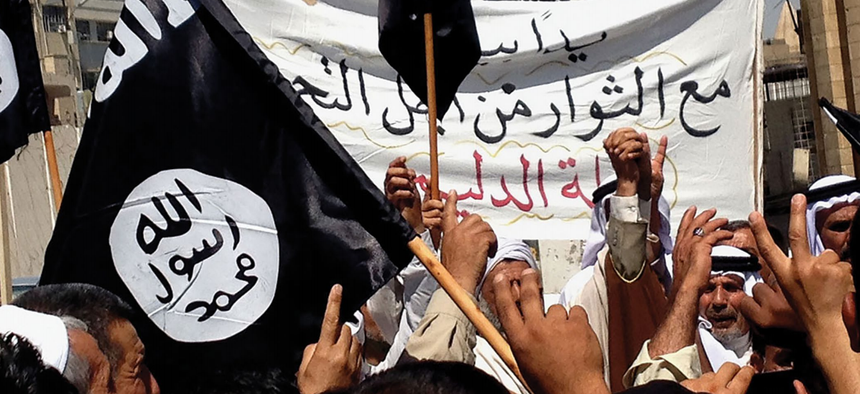 Demonstrators chant pro-Islamic State slogans as they wave the group’s flags 16 June 2014 in front of the provincial government headquarters in Mosul, Iraq.