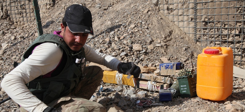 An Afghan Civilian Mine Removal Group (CMRG) member investigates IEDs during a training simulation in Panjwai district, Kandahar province, Afghanistan, Nov. 19, 2013.