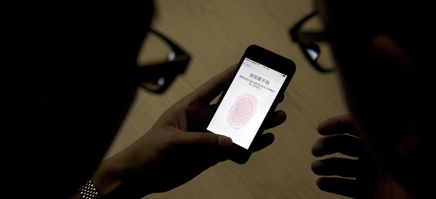 An Apple employee instructs a journalist on the use of the fingerprint scanner technology built into the company's iPhone 5S during a media event in Beijing, Sept. 11, 2013.