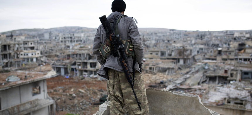 In this Jan. 30, 2015 file photo, a Syrian Kurdish sniper looks at the rubble in the Syrian city of Ain al-Arab, also known as Kobani. 