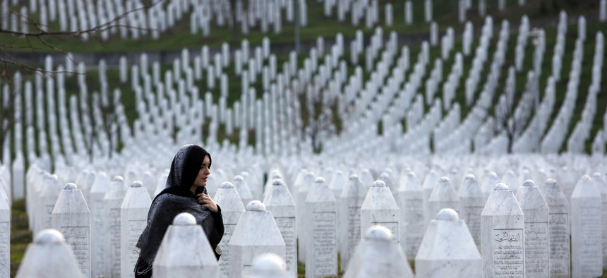 A Bosnian woman walks among gravestones at Memorial Centre Potocari near Srebrenica, Bosnia and Herzegovina.