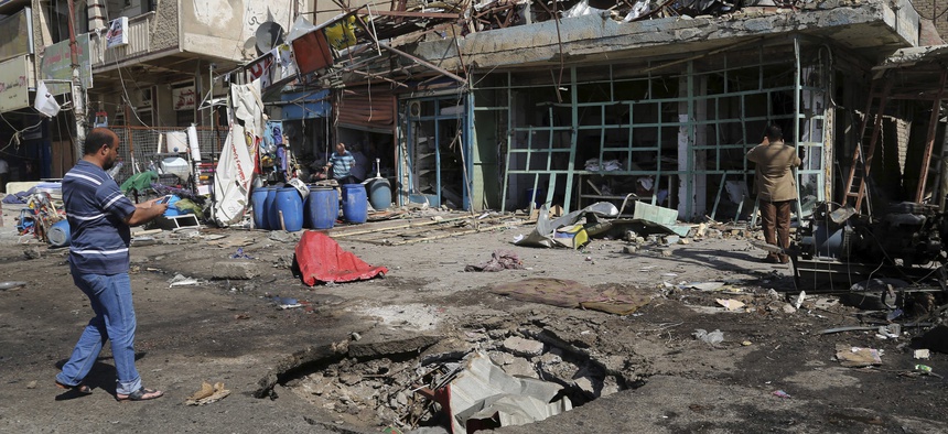 A civilian inspects a crater caused by a car bomb explosion in Baghdad, Iraq, Friday, Sept. 12, 2014.