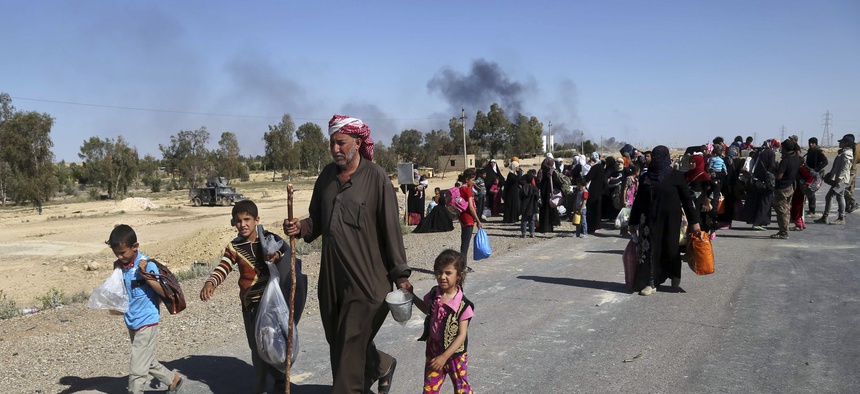 People flee their homes during clashes between Iraqi security forces and Islamic State group in Hit, 85 miles (140 kilometers) west of Baghdad, Iraq, Monday, April 4, 2016.