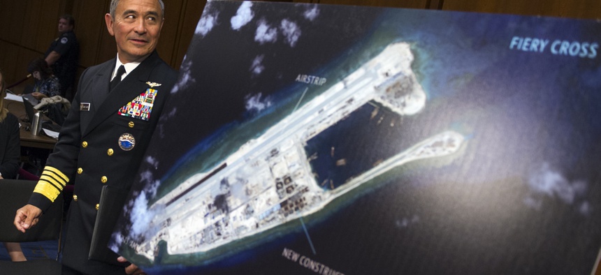 Adm. Harry Harris, commander of U.S. Pacific Command, walks past a photograph showing an artificial island China has built on the Fiery Cross Reef before an October 2015 congressional hearing.