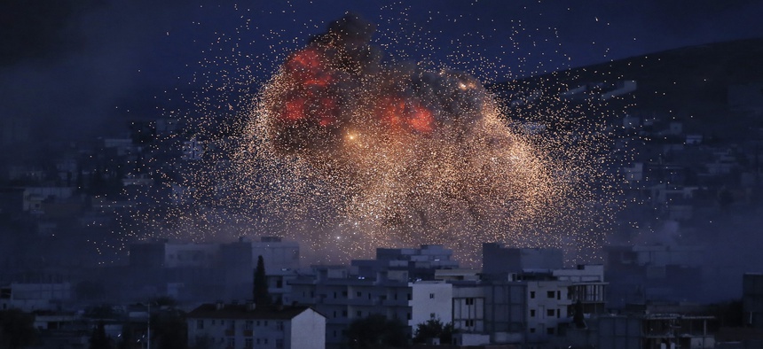In this Oct. 20, 2014 file photo, thick smoke and flames erupt from an airstrike by the U.S.-led coalition in Kobani, Syria, as seen from a hilltop on the outskirts of Suruc, at the Turkey-Syria border.