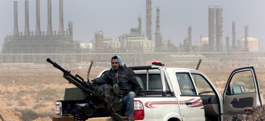 An anti-government rebel sits with an anti-aircraft weapon in front an oil refinery in Ras Lanouf, eastern Libya, March 5, 2011.