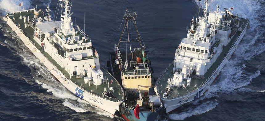 A boat, center, is surrounded by Japan Cost Guard's patrol boats after some activists descended from the boat on Uotsuri Island, one of the islands of Senkaku in Japanese and Diaoyu in Chinese, in East China Sea, Aug. 15, 2012.