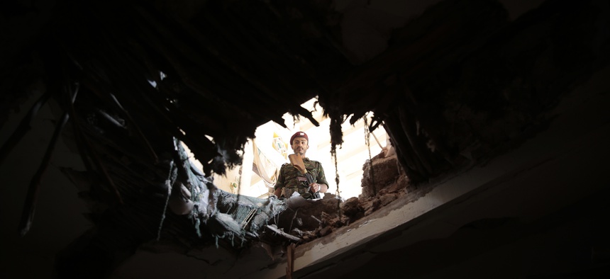 A soldier looks through a hole in a building damaged after an airstrike by Saudi-led coalition in Sanaa, Yemen, Tuesday, Sept. 20, 2016.