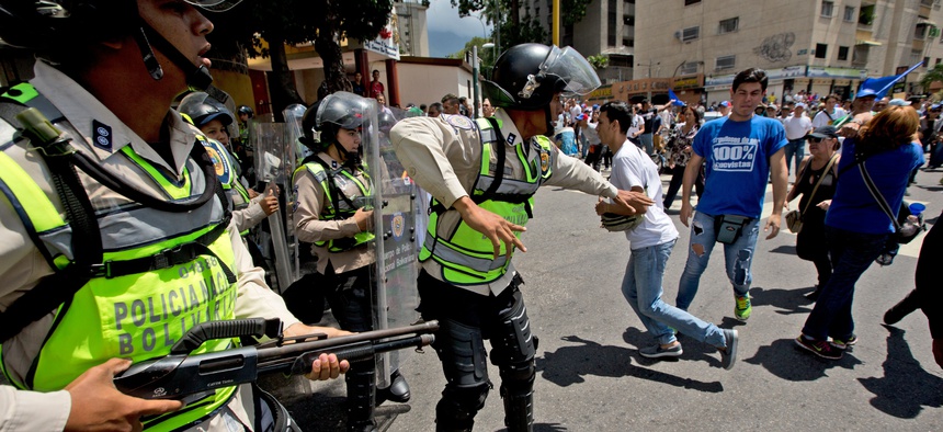 Bolivarian National Police officer try to disperse demonstrators during an opposition protest in Caracas, Venezuela, Friday, Sept. 16, 2016.