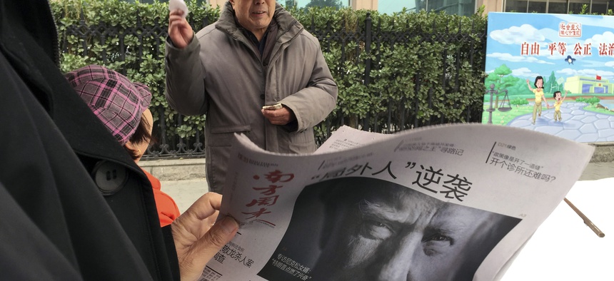 In this Nov. 10, 2016 file photo, a Chinese man holds up a Chinese newspaper with the front page photo of U.S. President-elect Donald Trump and the headline "Outsider counter attack" at a newsstand in Beijing, China.