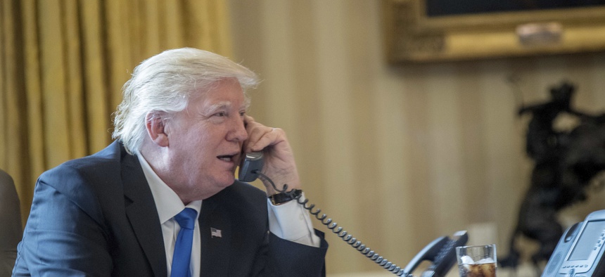 President Donald Trump speaks on the phone with Russian President Vladimir Putin, Saturday, Jan. 28, 2017, in the Oval Office at the White House in Washington.