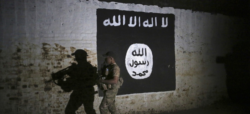 An Iraqi soldier inspects a recently-discovered train tunnel, adorned with an Islamic State group flag.