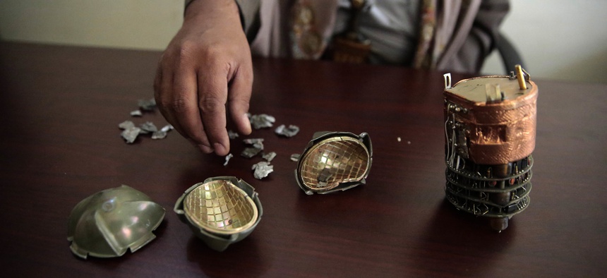 A Yemeni official displays cluster bomblet fragments from an unidentified source at a police compound in Sanaa, Yemen, Oct. 5, 2016.
