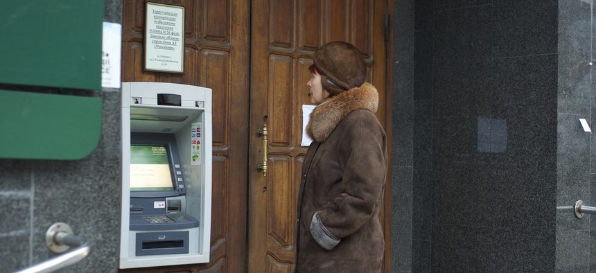 A woman stands at an ATM that doesn't work outside a Ukrainian bank in Donetsk, eastern Ukraine, Tuesday, Nov. 25, 2014.
