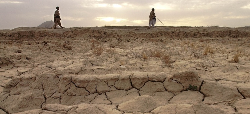 Two men walk along a ridge behind the cracked earth that should be a wheat field in Salawath, Afghanistan, March 10, 2002.