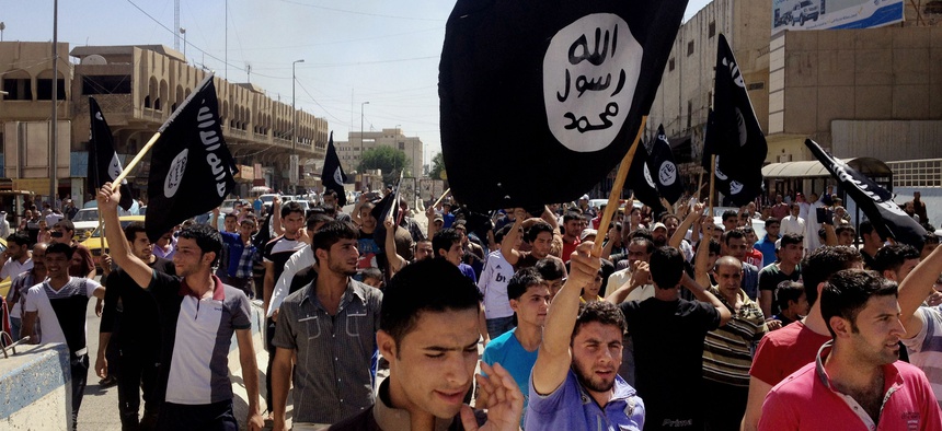 In this June 16, 2014 file photo, demonstrators chant pro-Islamic State group, slogans as they carry the group's flags in front of the provincial government headquarters in Mosul, 225 miles (360 kilometers) northwest of Baghdad.