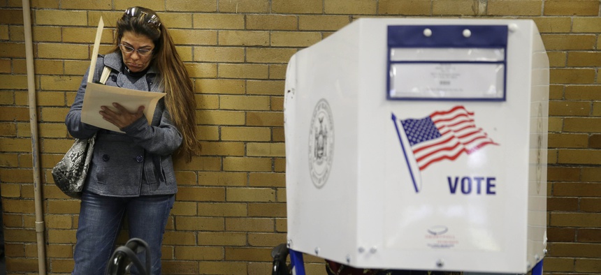 Because all the privacy booths are full, Miriam Rodriguez fills out her ballot while leaning against the wall at a polling site in New York, Tuesday, Nov. 4, 2014.