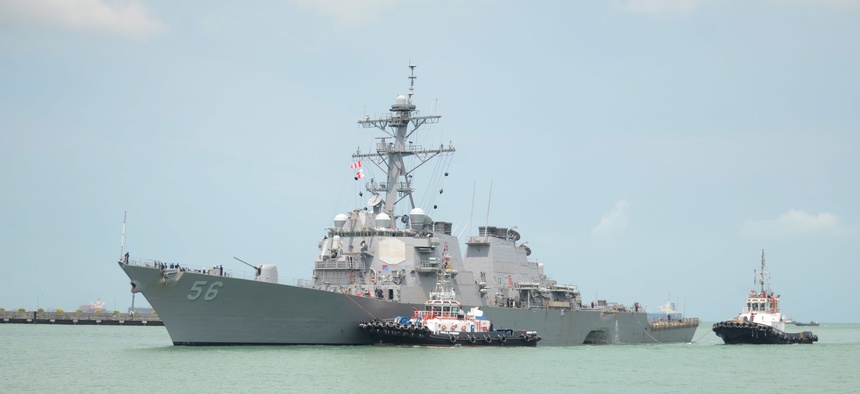 Tugboats from Singapore assist the Guided-missile destroyer USS John S. McCain as it steers towards Changi Naval Base, Republic of Singapore following a collision with the merchant vessel.
