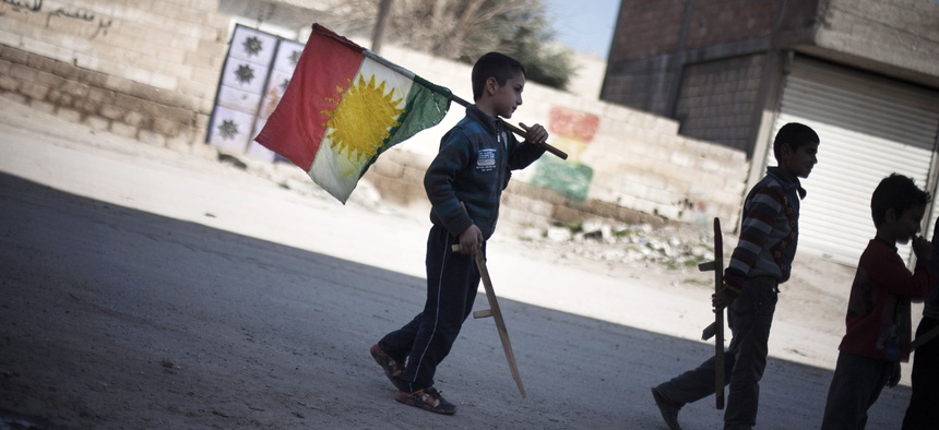 In this Monday, Feb. 26, 2013 file photo, a boy carries a Kurdish flag as he and others hold toy guns.