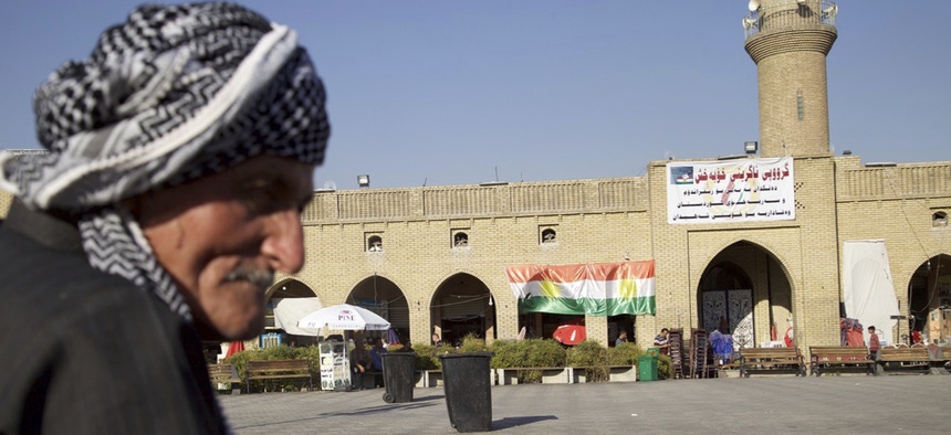 Saber Salim sits outside Irbil's Citadel near a campaign poster urging people to vote 'yes' in September's schedule referendum on independence from Iraq, Aug. 24, 2017.