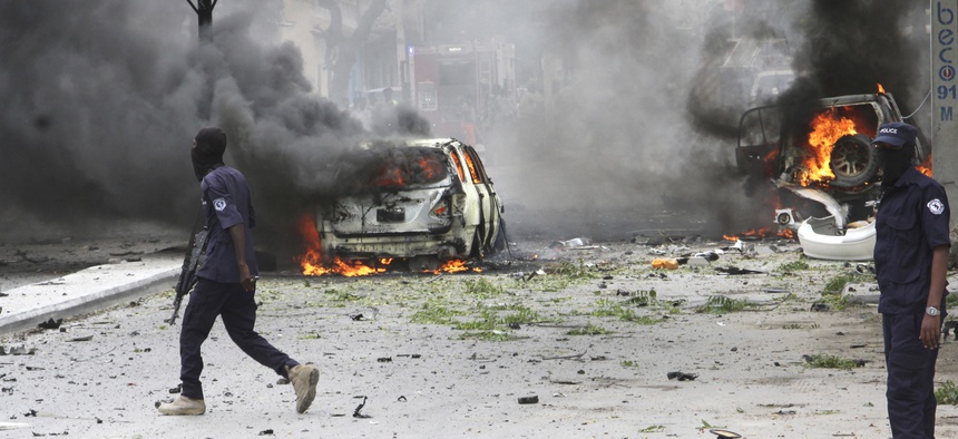 Somali soldiers pass burning vehicles outside Midnimo mall after a car bomb attack on a popular mall in Mogadishu earlier this summer.