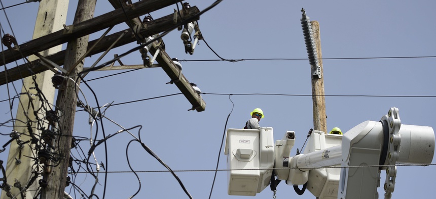 In this Thursday, Oct. 19, 2017 photo, a brigade from the Electric Power Authority repairs distribution lines damaged by Hurricane Maria in the Cantera community of San Juan, Puerto Rico.