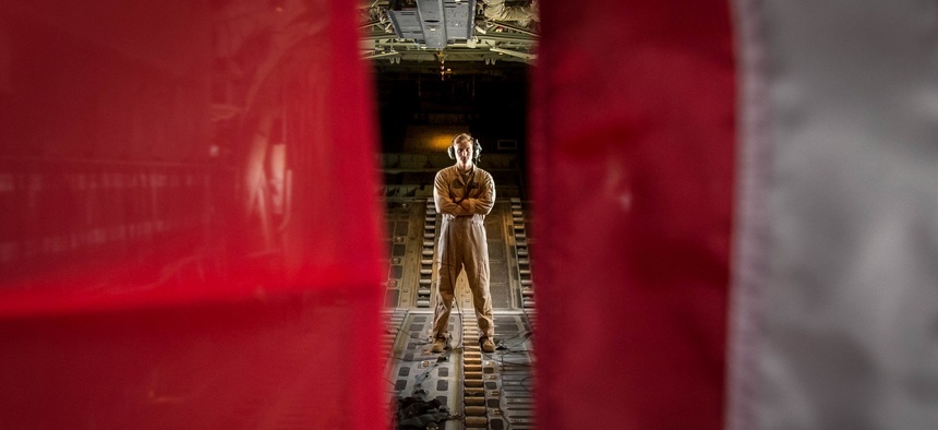 A U.S. Marine poses in between the U.S. Marine Corps flag and U.S. American flag in a KC-130J Super Hercules while forward deployed in the Middle East, Sept. 3, 2017.