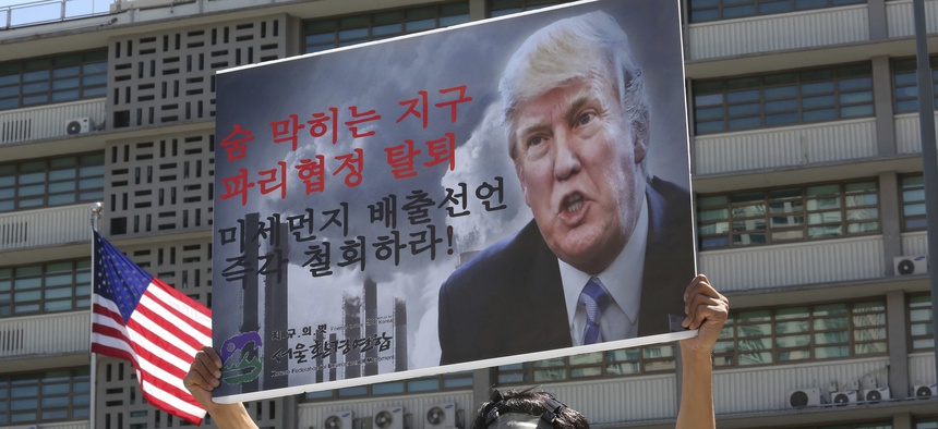 A South Korean environmental activist wearing a gas mask participates in a protest to denounce the U.S. withdrawal from the Paris climate accord, in front of the U.S. Embassy in Seoul, South Korea, Monday, June 5, 2017.