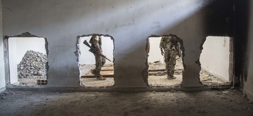 Members of the U.S.-backed Syrian Democratic Forces (SDF) walk inside the stadium that was the site of Islamic State fighters' last stand in the city of Raqqa, Syria, Friday, Oct. 20, 2017.