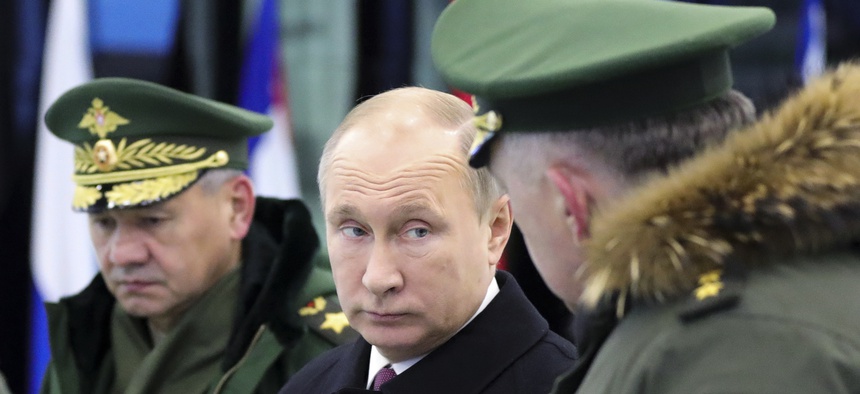 Russian President Vladimir Putin speaks to Russian Strategic Missile Troops Commander, Col. Gen. Sergei Karakayev, right, as Russian Defence Minister Sergei Shoigu looks on outside Moscow, Russia, Dec. 22, 2017.