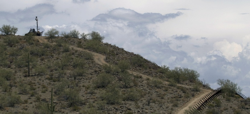 A US National Guard vehicle guards covered under camouflage fabric sits atop a mountain next to the border fence near Sonoyta, Mexico, Thursday, July 29, 2010.
