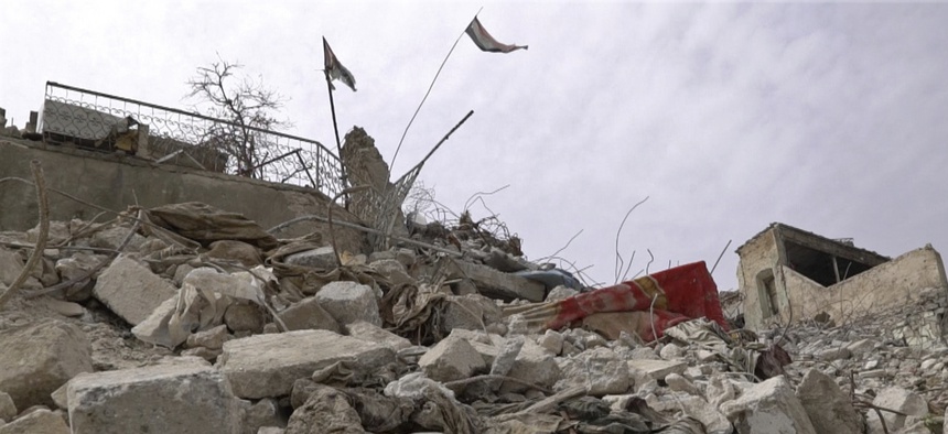 In this frame grab from video, a body lies under the Iraqi flag in the Maydan district of Mosul's Old City, Iraq, Wednesday, March 7, 2018.