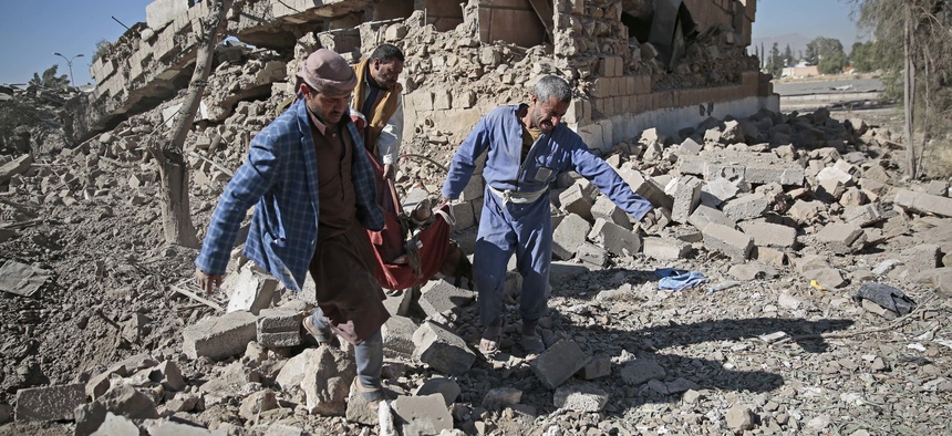 People carry the body of a man they uncovered from under the rubble of a Houthi-held detention center destroyed by Saudi-led airstrikes in Sanaa, Yemen, Wednesday, Dec. 13, 2017