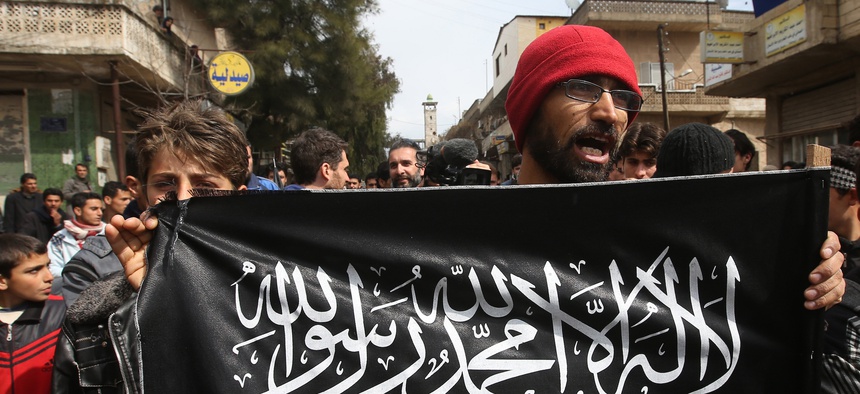 A 2013 photo of a man holding a Jabhat al-Nusra flag in Syria's Idlib province. The group has since rebranded itself Hayat Tahrir al-Sham, or HTS.