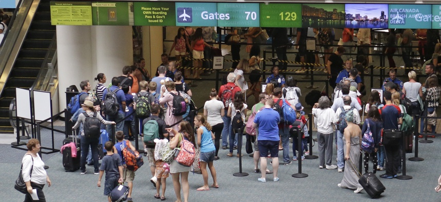 Passengers line up at security check points before heading to their departure gates at Orlando International Airport in Orlando, Fla.
