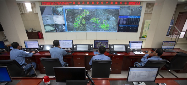 Workers sit at computer terminals as they monitor a large display screen in the command center at the Sinopec Yanshan Petrochemical Company on the outskirts of Beijing, Friday, May 25, 2018.