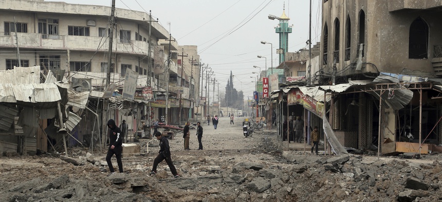 Civilians walk amid the rubble after fight between Iraqi security forces against Islamic State militants in the eastern side of Mosul, Iraq, Saturday, Jan. 21, 2017.