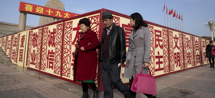In this Nov. 4, 2017 photo, residents walk past a statue showing Mao Zedong near billboards with the words for "Welcome 19th Congress," "Patriotism" and "Democracy" near a square in Kashgar in Xinjiang, China.