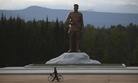 In this photo taken Friday, Aug. 17, 2018, a North Korean man pushes his bicycle past a monument to late North Korean leader Kim Il Sung at the Samjiyon Great Monument in Samjiyon, North Korea. 
